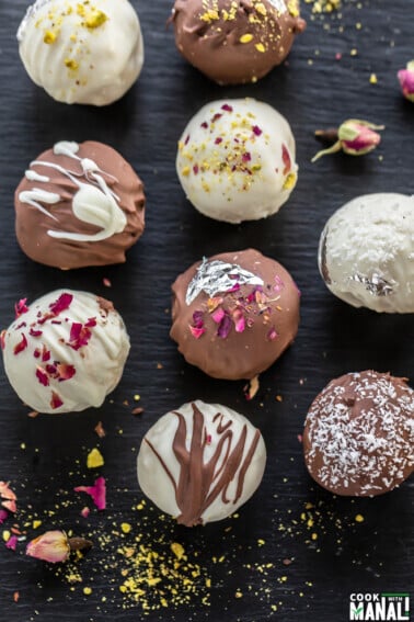 burfi truffles topped with nuts, rose petals arranged on a black board