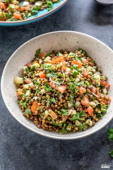 bowl of lentil salad garnished with mint and parsley