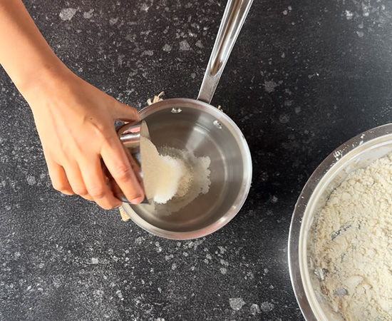 sugar being added to a pan filled with water